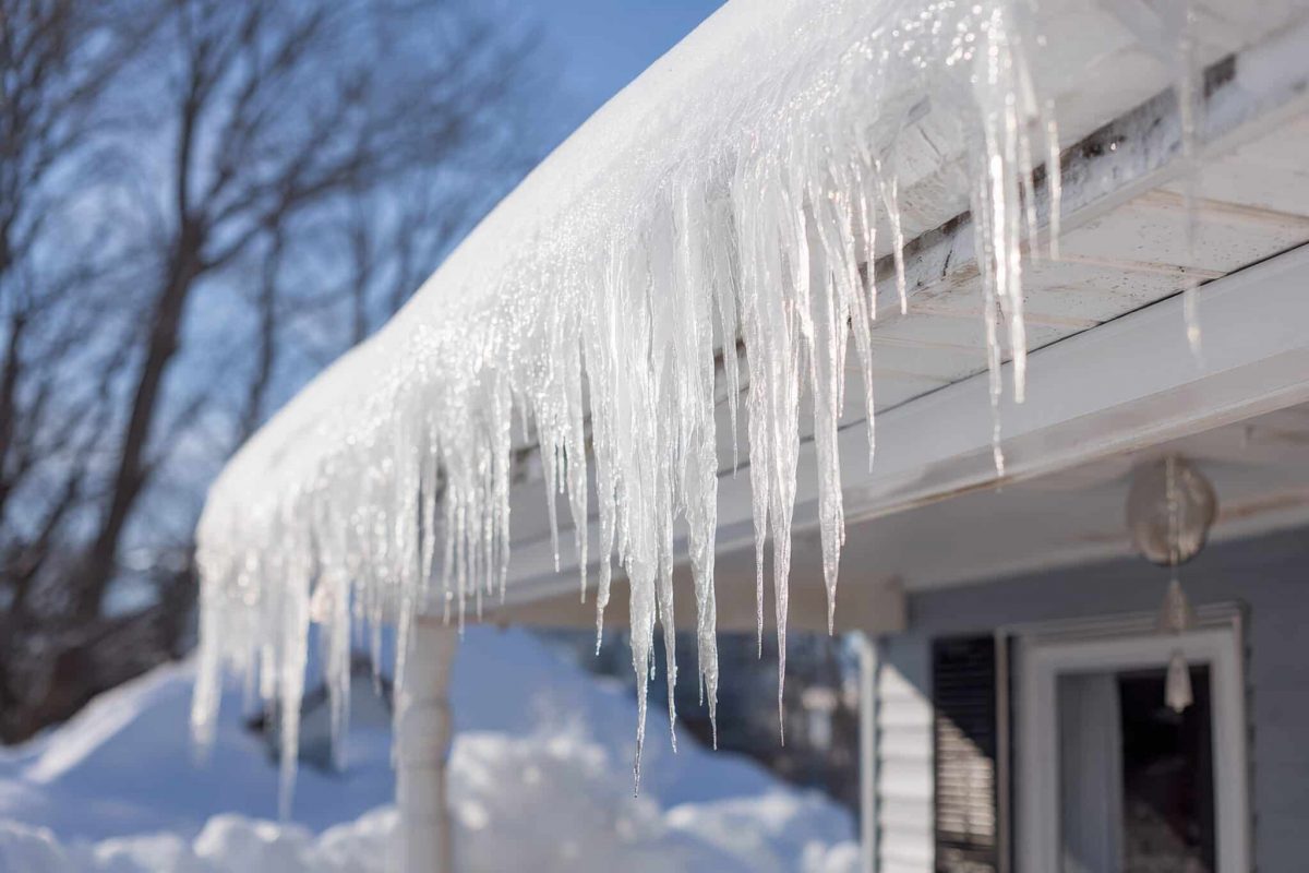 Icicles hang from the edge of a roof, signaling the potential for ice dams. Homeowners should consider insulation and proper drainage to prevent water damage and roof issues in winter.